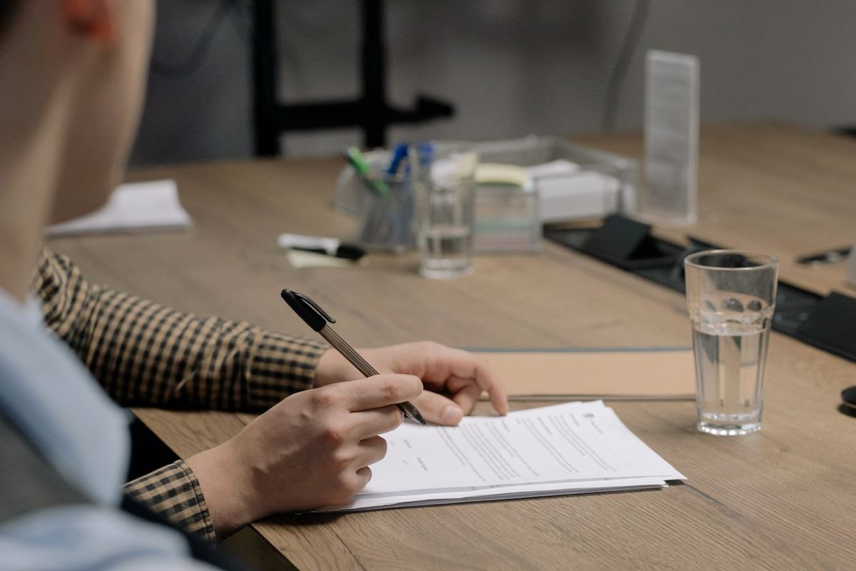 Persona firmando documentos de contrato de seguro en oficina