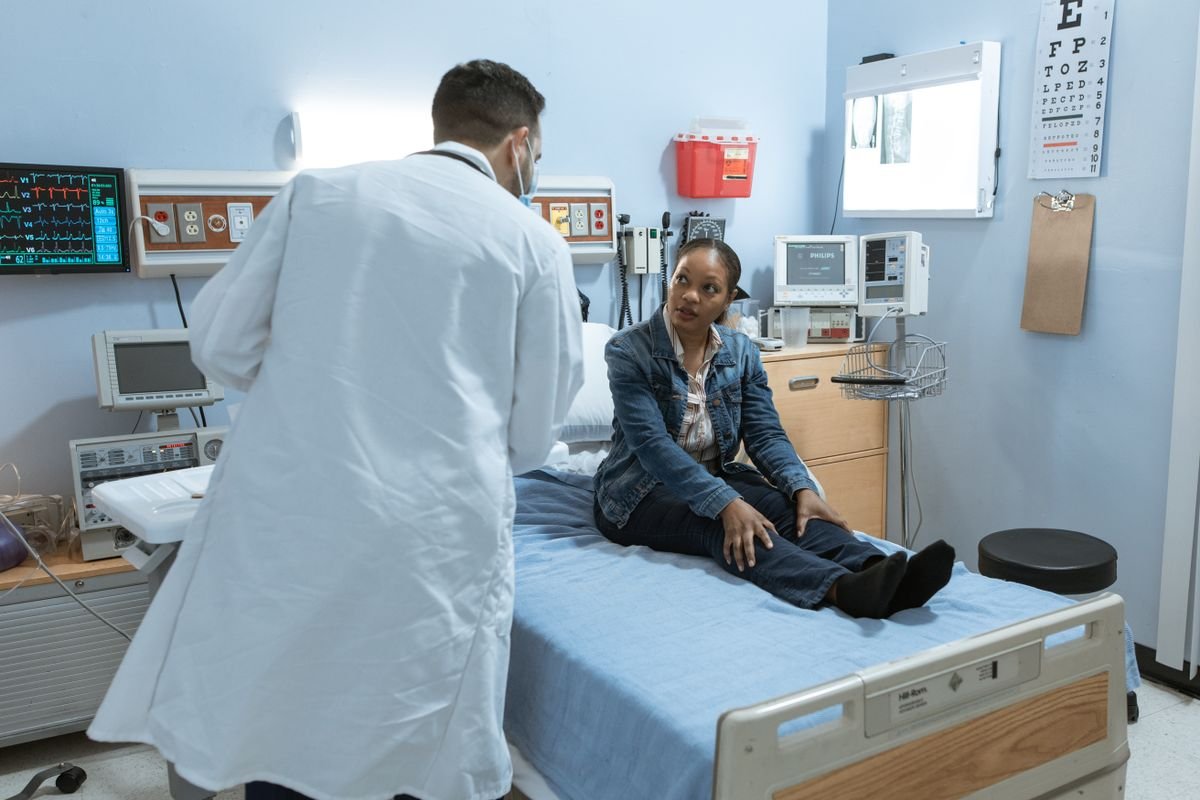 Médico consultando a un paciente sentado en una cama de hospital, atención personalizada