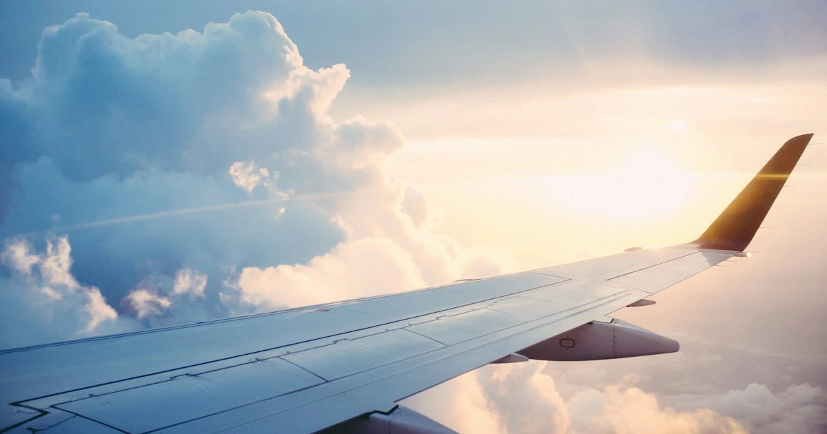 Avión comercial volando sobre las nubes al atardecer en un viaje internacional